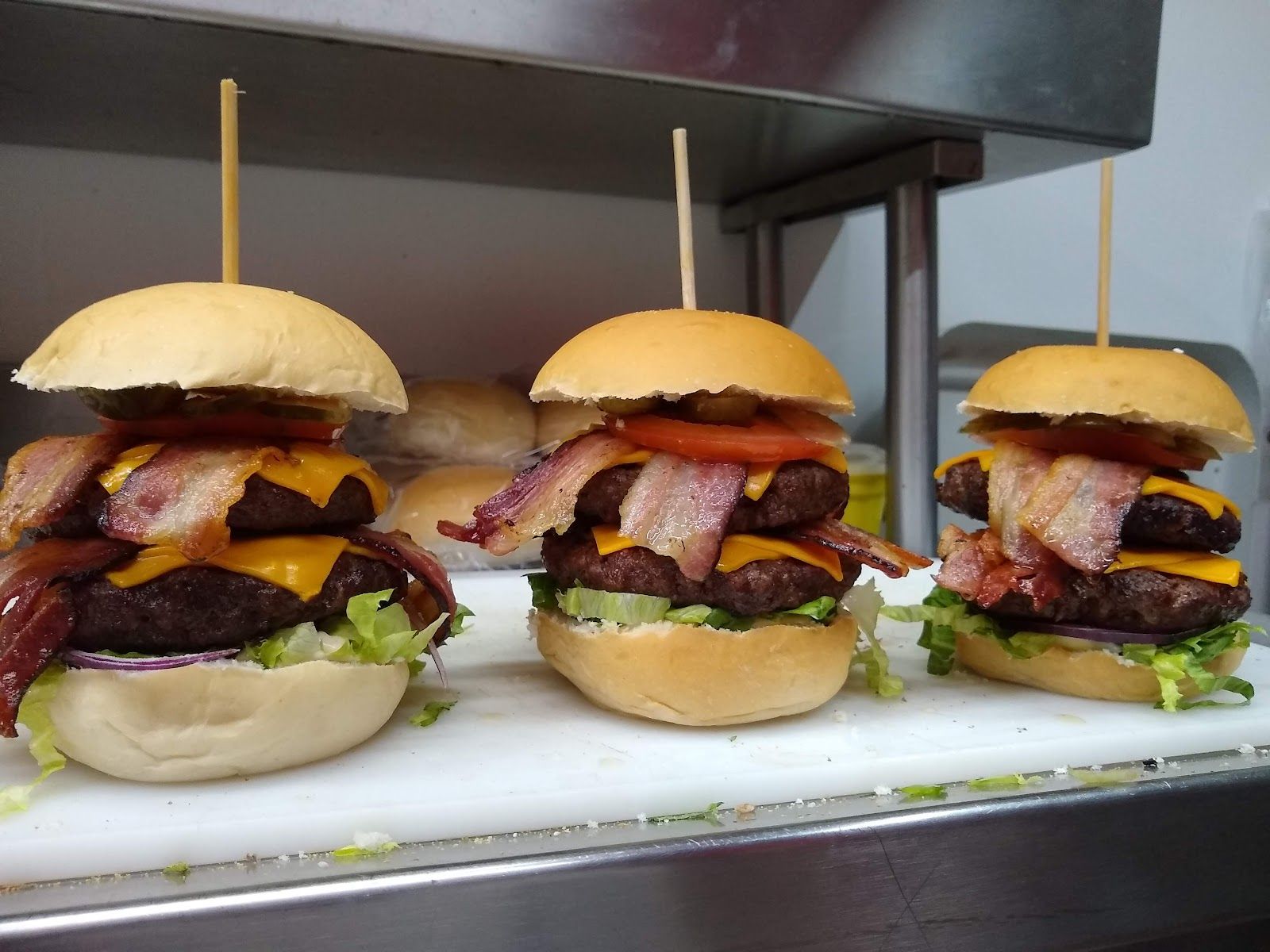 Três hambúrgueres com bacon e cheddar